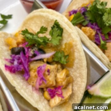 Small chicken tacos in a serving rack with lime, cilantro and salsa on the side.