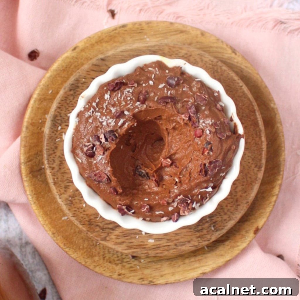 Velvety Vegan Chocolate Avocado Dream 2 Rich Vegan Avocado Chocolate Mousse in a small white bowl, viewed from above, garnished with cacao nibs.