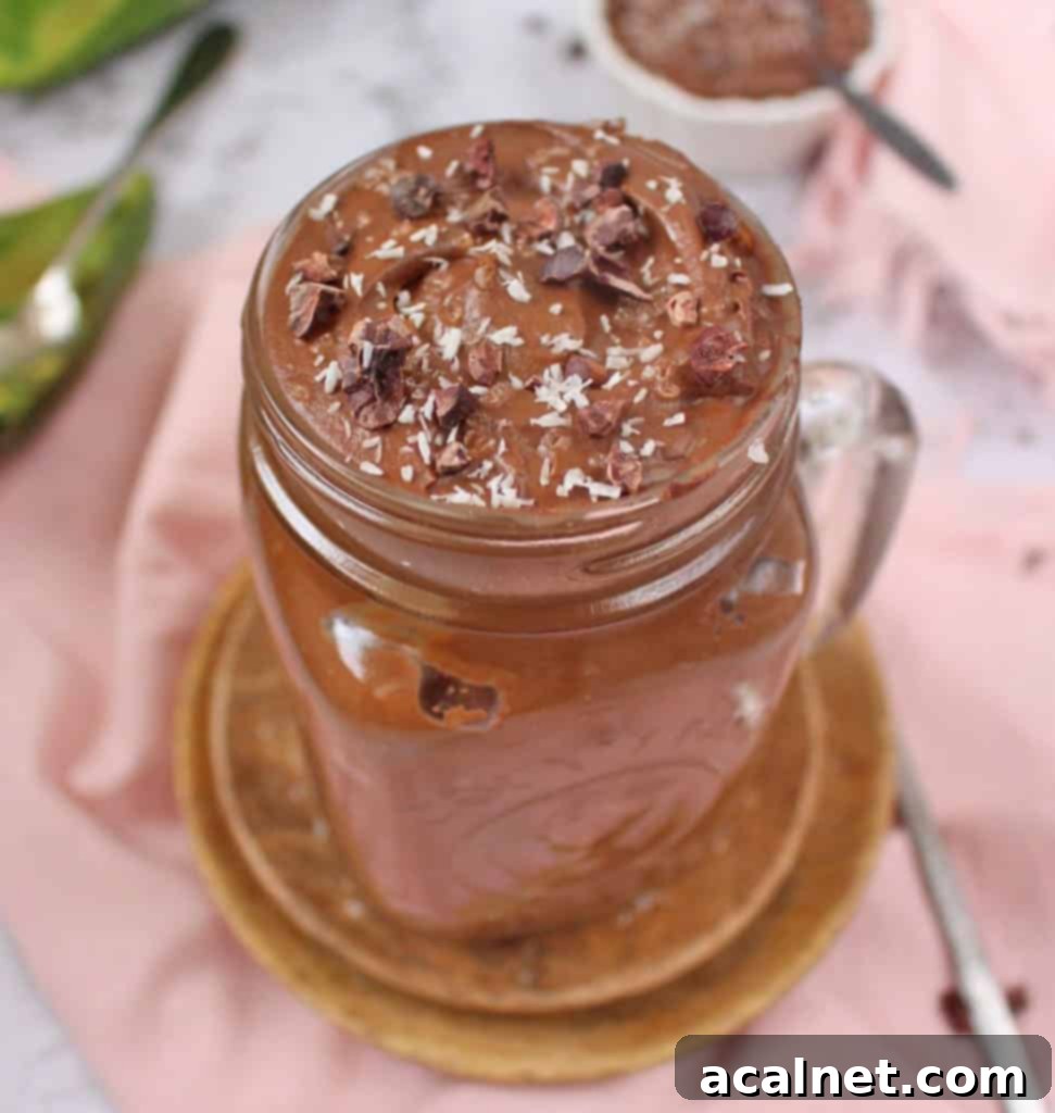 Velvety Vegan Chocolate Avocado Dream 5 Vegan Chocolate Avocado Mousse topped with shredded coconut and cacao nibs in a white bowl.