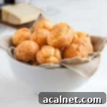 Cheese puffs in a white bowl over a beige napkin.