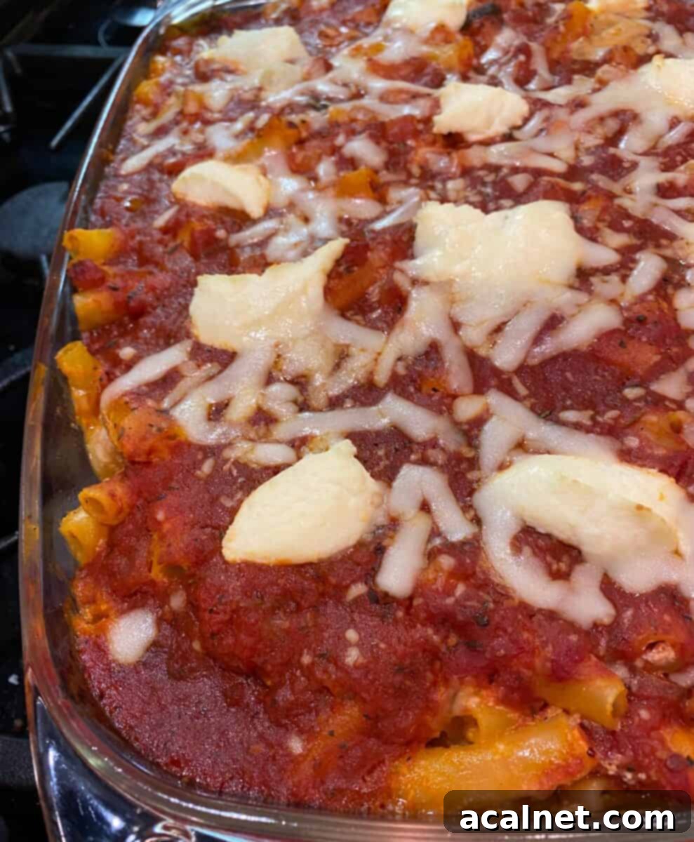 Ultimate Cheesy Ziti Bake 2 A large rectangular baking dish filled with Cheesy Baked Ziti Casserole, featuring golden-brown melted cheese, vibrant red sauce, and visible ziti pasta peeking through.