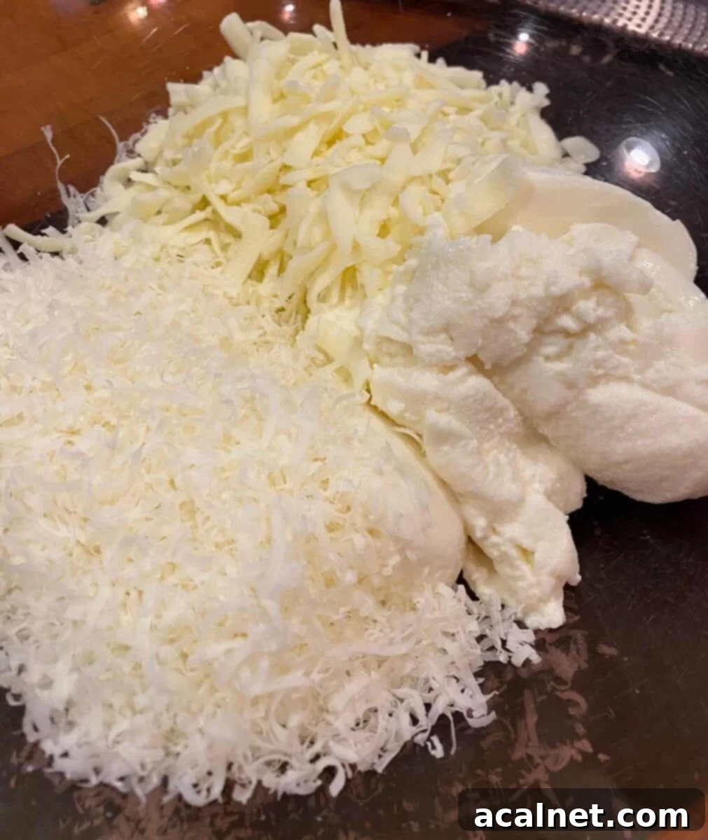 Ultimate Cheesy Ziti Bake 4 A large clear bowl filled with a mixture of ricotta, shredded mozzarella, and grated Parmesan cheese, ready for the ziti casserole.