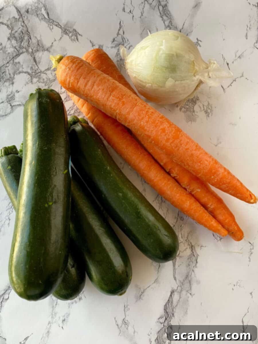 Four zucchinis, three carrots and an onion on a counter.