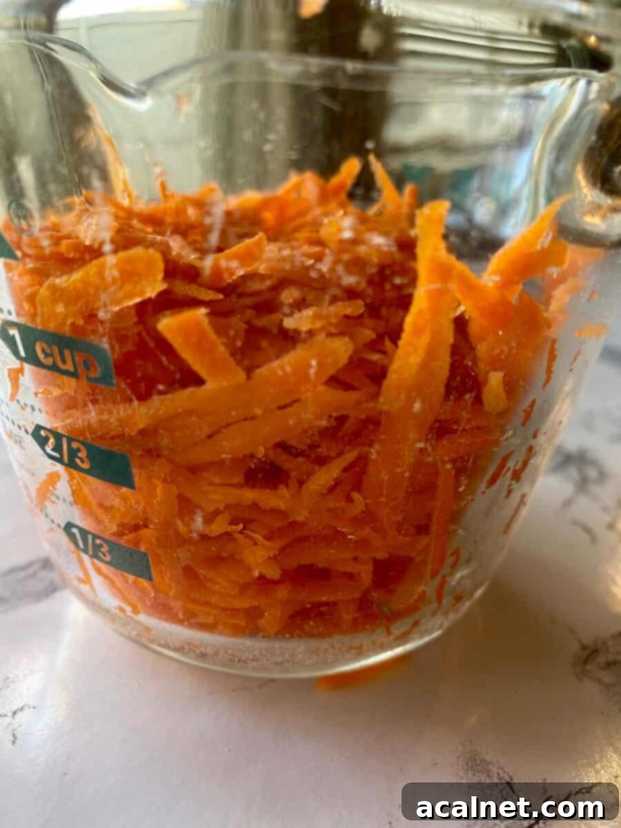 Grated carrots in a one-cup measuring bowl.