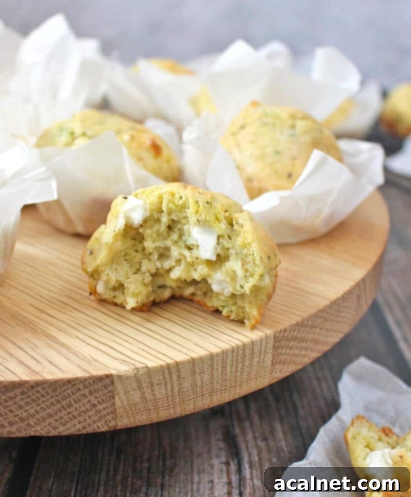Savory Zucchini and Goat Cheese Muffins 6 Crumb shot of a Savoury Cheese Zucchini Muffin sliced in half, showing its moist interior, melted goat cheese, and flecks of zucchini, placed on a rustic wooden board.