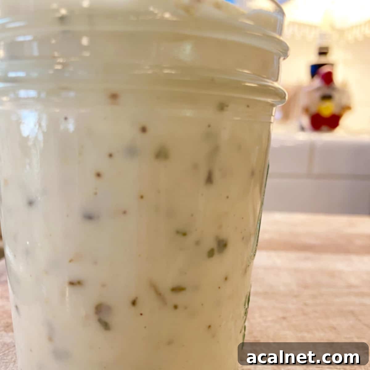 A small jar on a cutting board, full of garlic parmesan white pizza sauce.