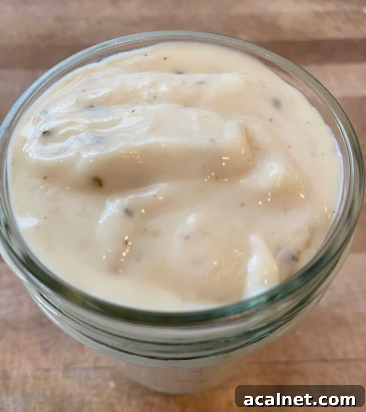 White pizza sauce in a small glass jar.