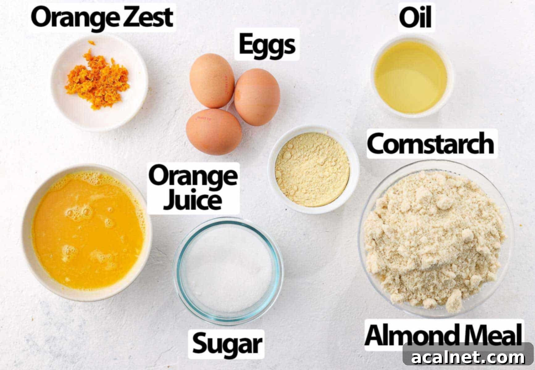 Zesty Gluten Free Almond Orange Cake 3 A flat lay image displaying all the individual ingredients for the Almond Orange Cake on a white surface.