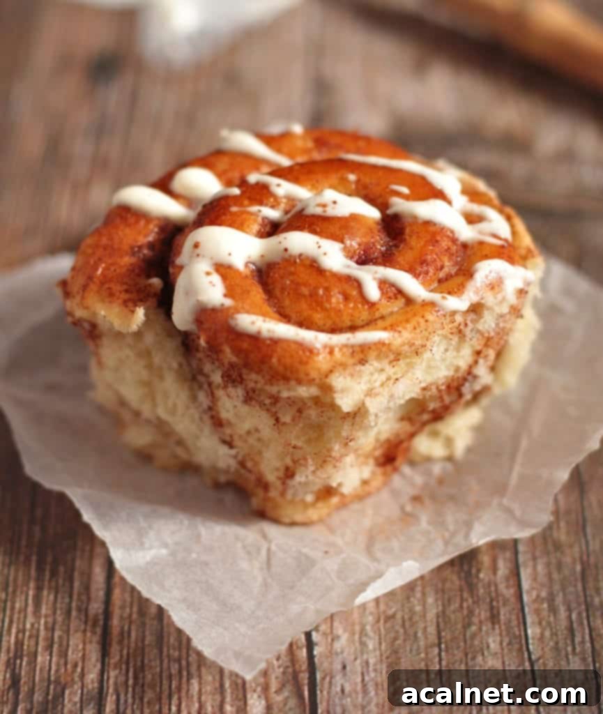 One roll on baking paper over a wooden surface with the yogurt drizzle