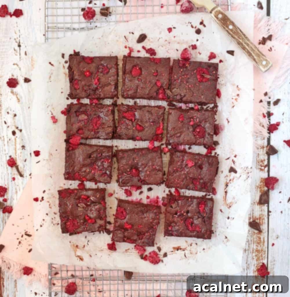 Fudgy brownies with raspberries from above on baking paper, showcasing their perfect bake.