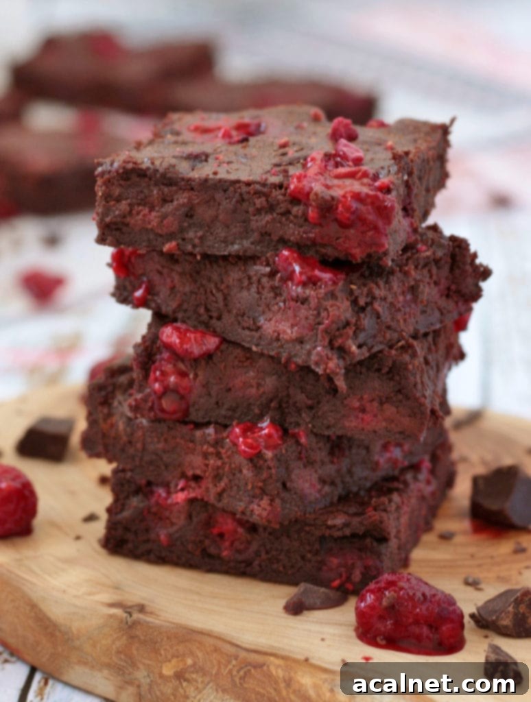 Close up on a Stack of Raspberry Brownies, highlighting their moist interior and vibrant raspberry pieces.