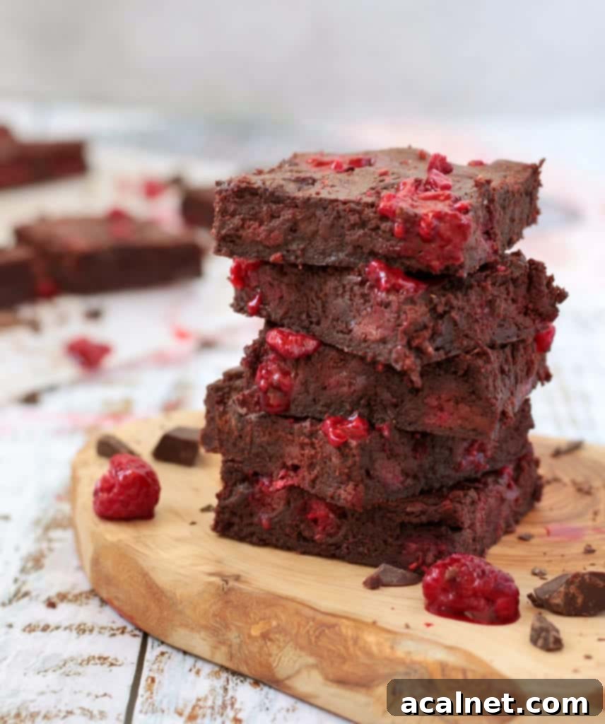 Stack of 5 slices of fudgy raspberry brownies on a wooden board, ready to be enjoyed.
