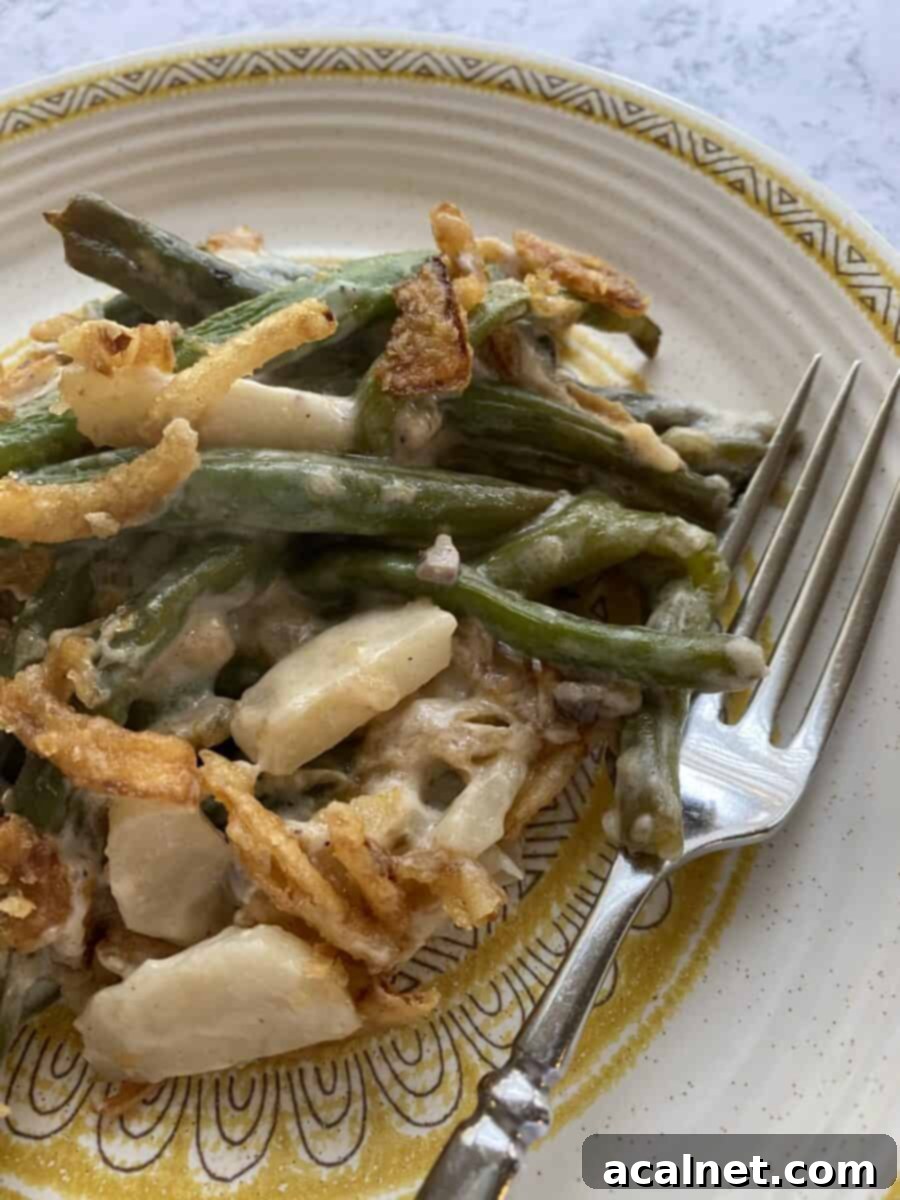 A close-up of the elegant green bean casserole after baking, showing the rich, creamy sauce generously coating each fresh green bean, with a hint of crispy onions on top.