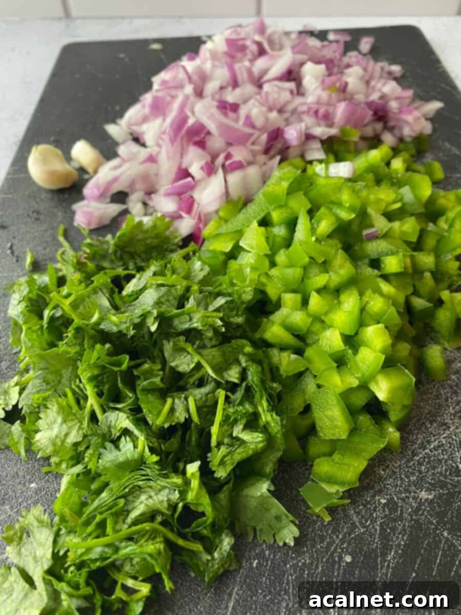 Finely diced red onion, green pepper, and fresh cilantro on a cutting board, ready for the Black-Eyed Pea Salad.