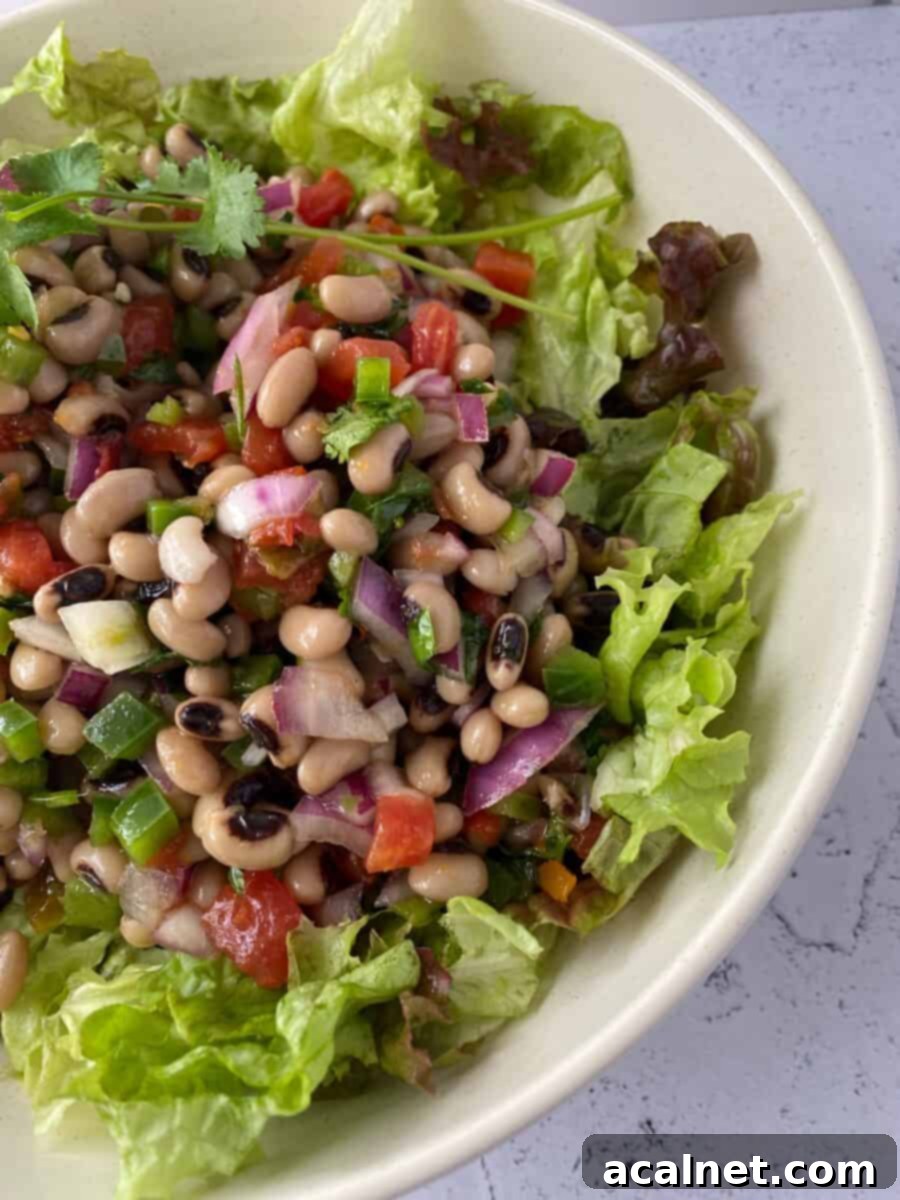 Spicy Black-Eyed Pea Salad in a serving bowl, viewed from the side, with visible fresh ingredients and dressing.