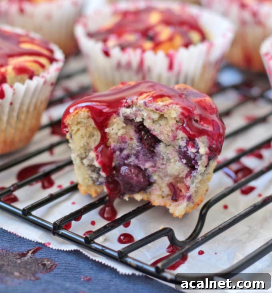A delicious crumb shot of a lemon blueberry muffin, cut in half, revealing the fluffy interior, bursting blueberries, and drizzled with glaze.