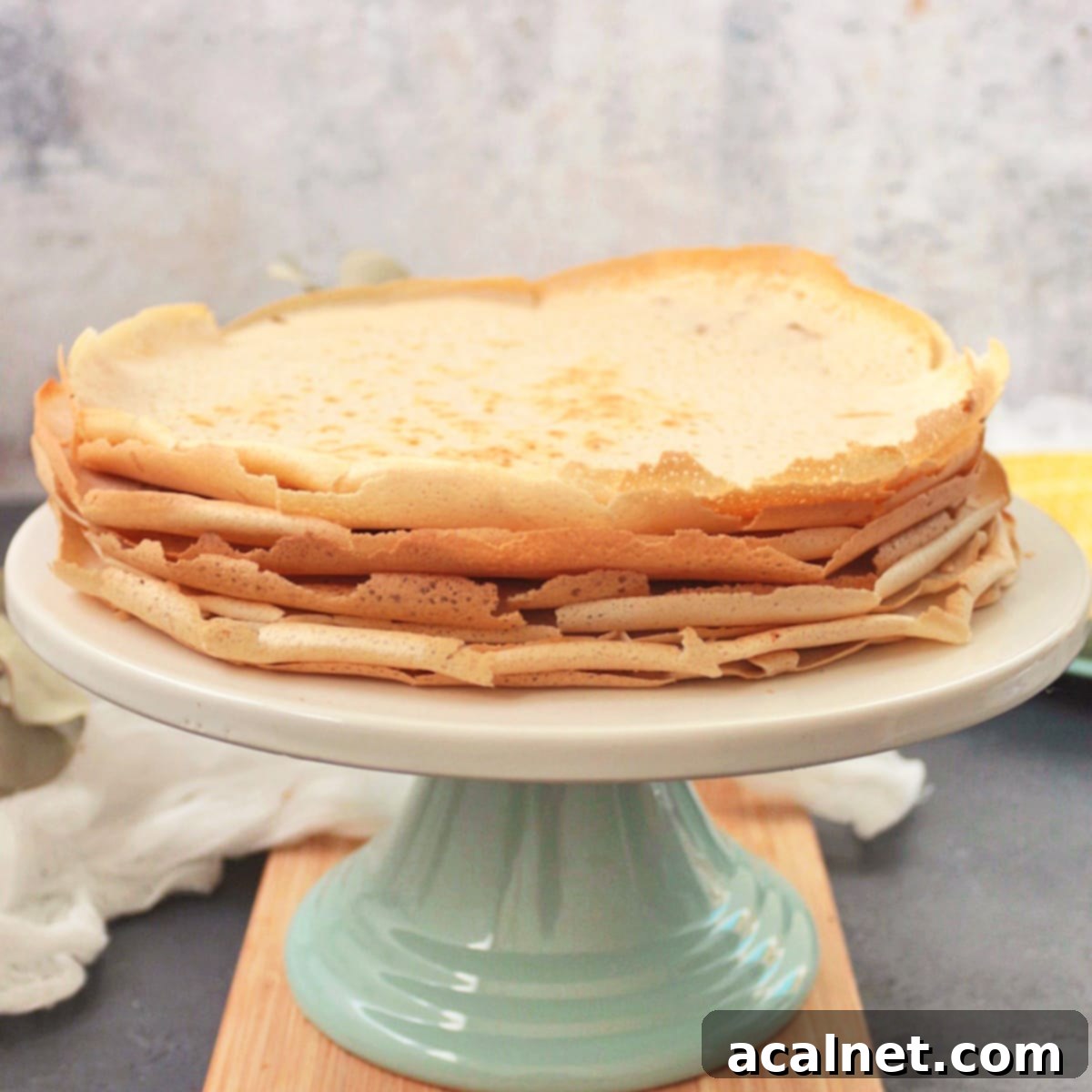 A stack of golden-brown Buckwheat Crêpes beautifully arranged on a cake stand, ready to be filled and enjoyed.
