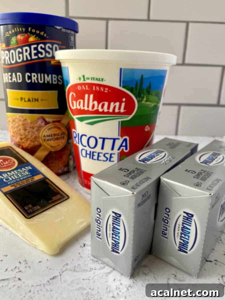 Cheesecake ingredients on a counter, cream cheese, parmesan cheese, ricotta cheese and a box of dry breadcrumbs.