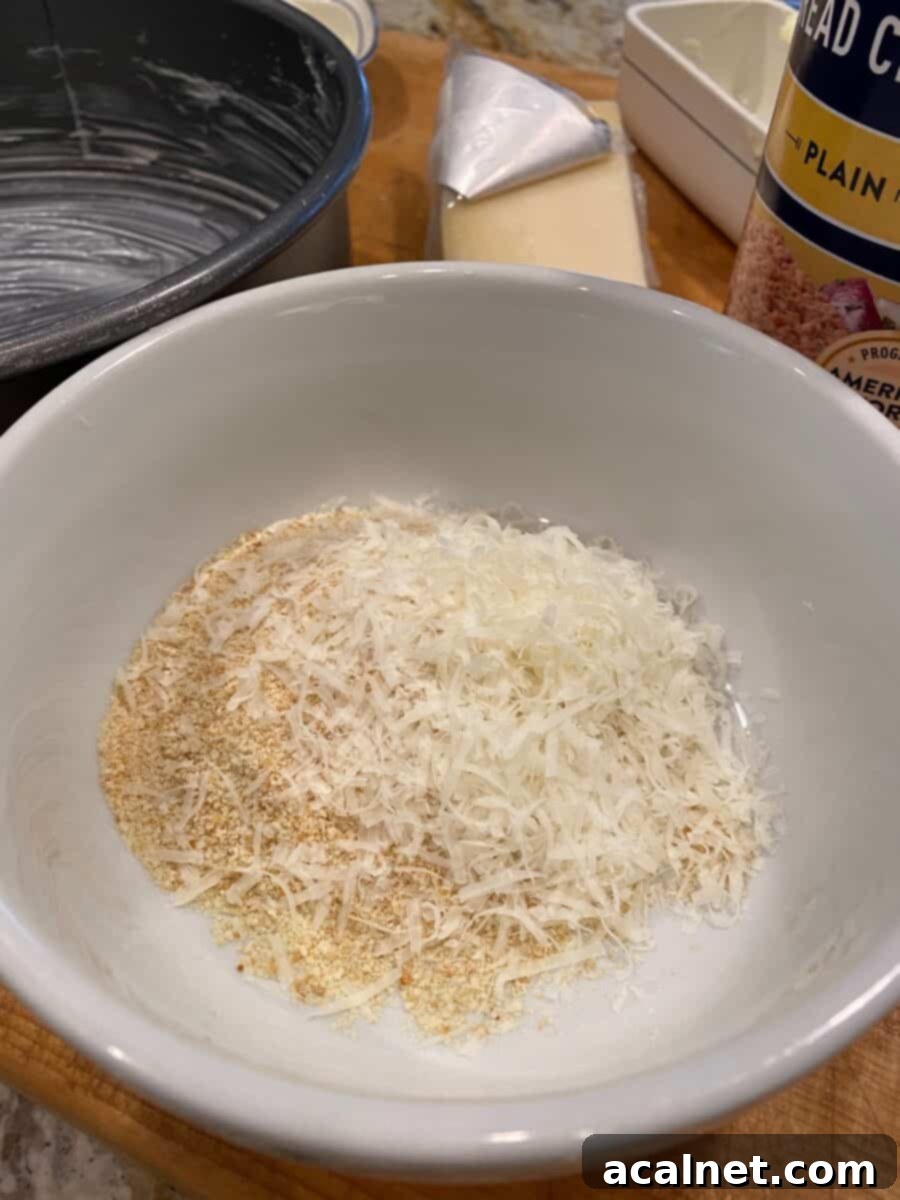 Dried bread crumbs and parmesan cheese in a small bowl on a cutting board.