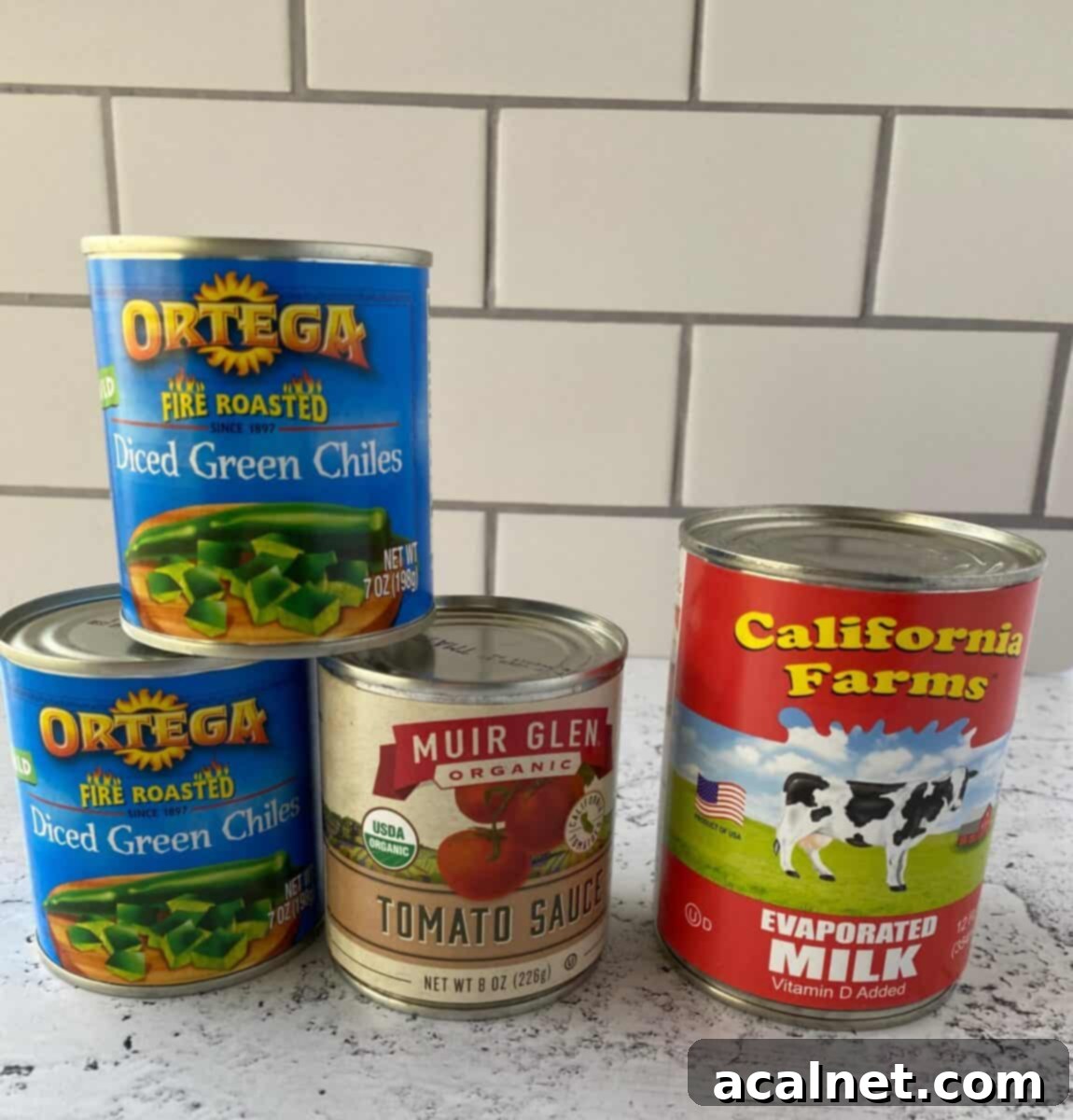 Fiesta Green Chile Egg Casserole 3 Canned ingredients for chili relleno casserole stacked on a counter, including evaporated milk, green chiles, and tomato sauce.