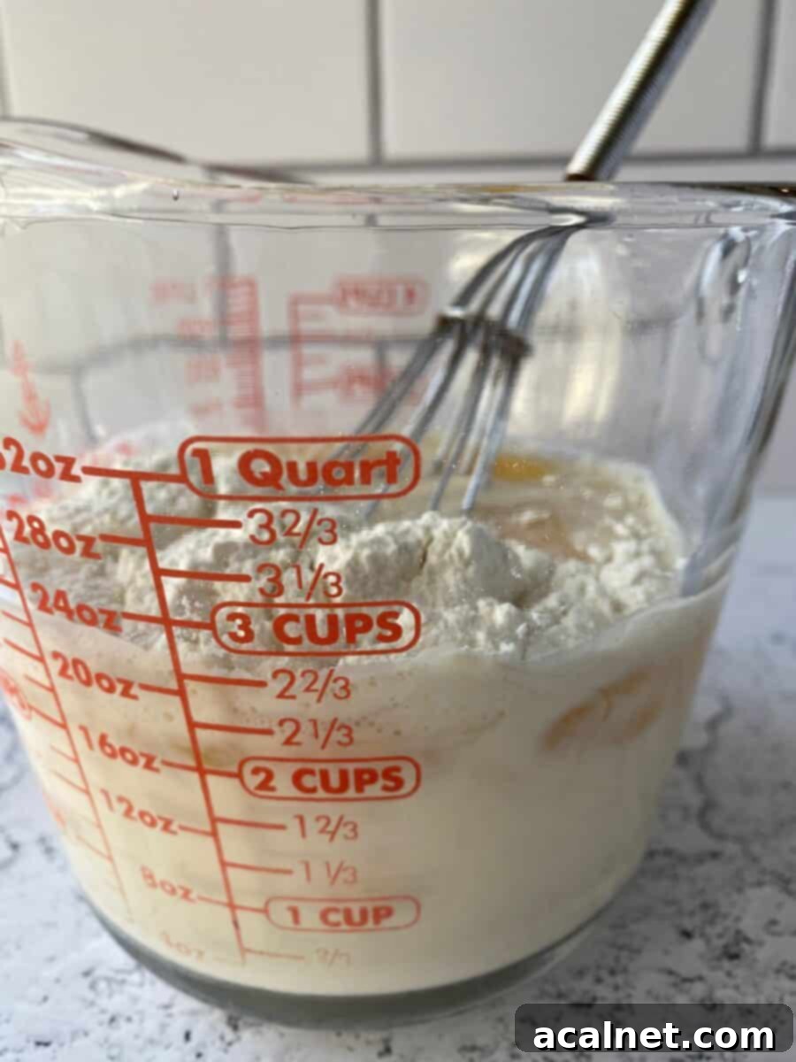 Fiesta Green Chile Egg Casserole 4 Evaporated milk, eggs, and flour being whisked in a glass measuring cup.