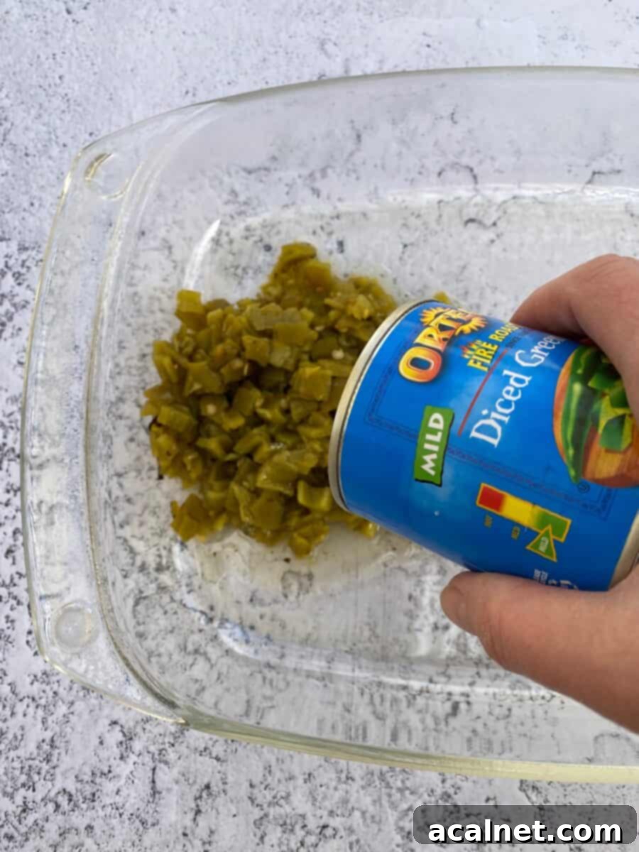 Fiesta Green Chile Egg Casserole 5 Canned diced green chiles being poured into a baking dish as the first layer.
