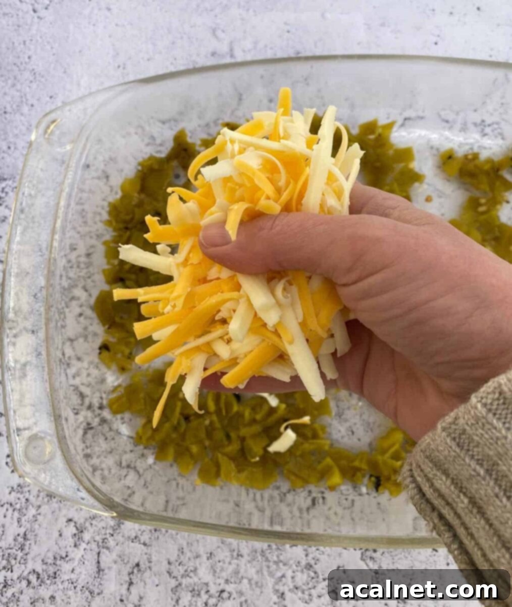 Fiesta Green Chile Egg Casserole 6 A handful of shredded cheese being sprinkled over a dish of green chiles.