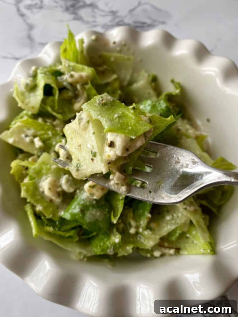 A fork full of green salad with copycat Buddy's Salad Dressing, held above a bowl of salad.