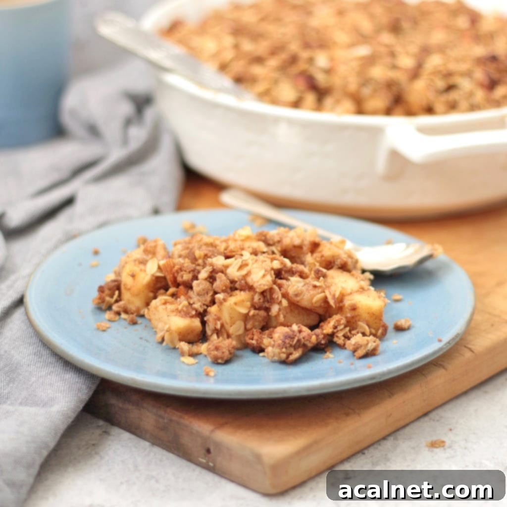 Warm apple and pear crumble served on a blue plate with a spoon, ready to be enjoyed.