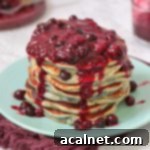 Close up on the blueberry sauce over the pancakes, highlighting the fluffy texture and juicy berries.