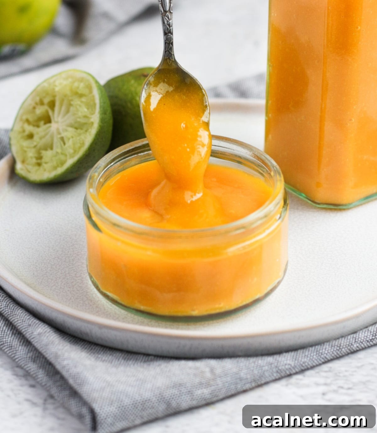 Ultimate Sweet Pancake Topping Guide 11 Pouring a vibrant mango coulis from a silver spoon over a glass cup.