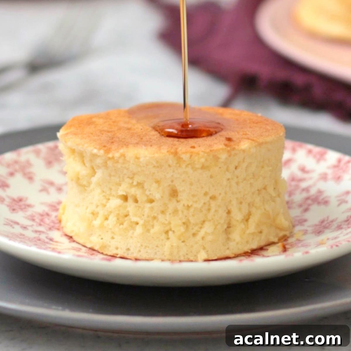 Ultimate Sweet Pancake Topping Guide 21 Syrup being generously poured over a stack of fluffy Japanese pancakes, with berries on the side.