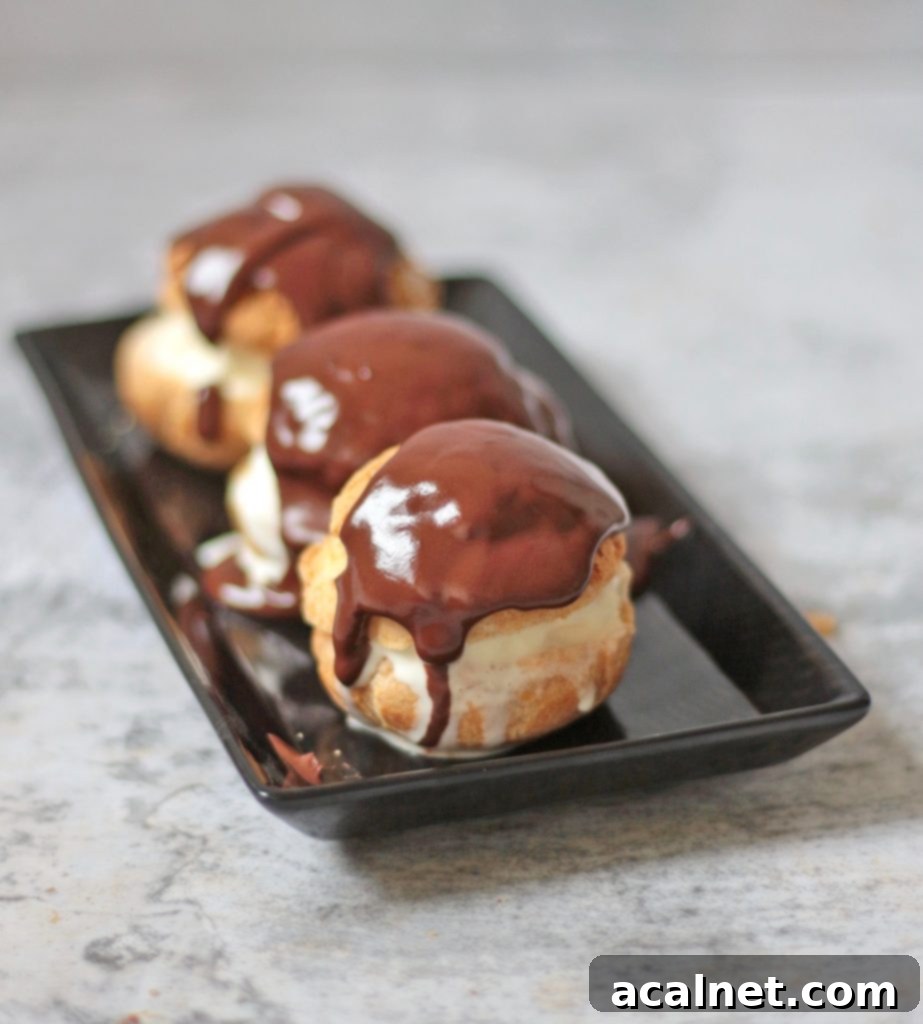 A trio of perfectly baked profiteroles on a white plate, ready for filling.