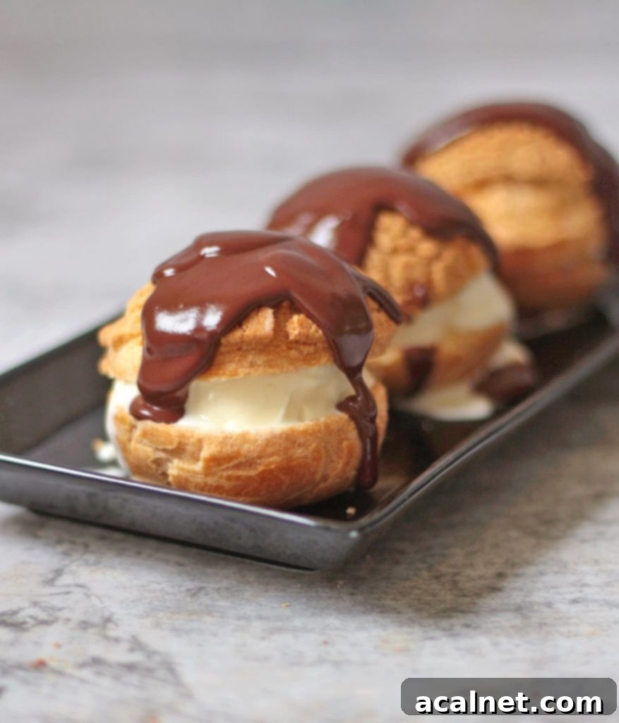 Close-up of a profiterole cut open, revealing vanilla ice cream filling, with chocolate sauce drizzled over.