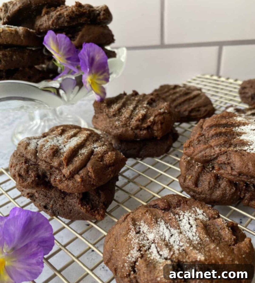 Freshly baked Molasses Snaps cooling on a wire rack, with a vibrant pansy flower for garnish.