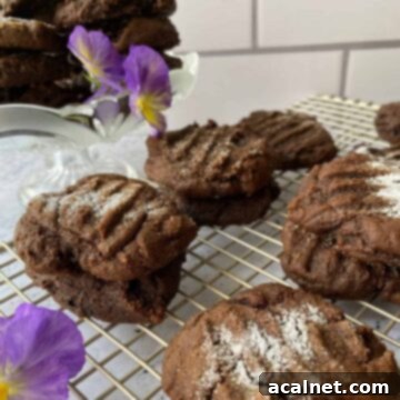 A plate of fresh Molasses Snaps cooling on a wire rack, with a delicate pansy nearby.
