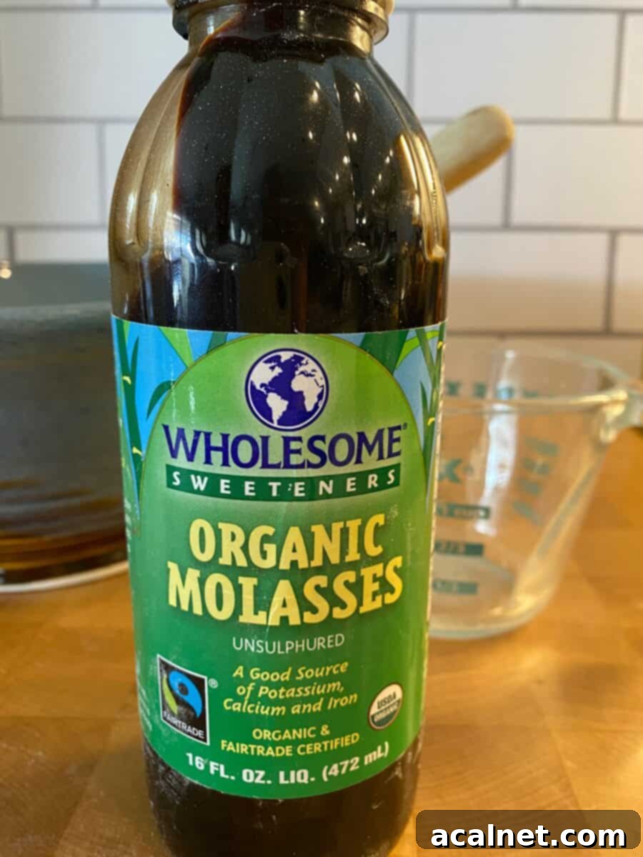 A classic jar of dark, rich molasses sits prominently on a kitchen counter, ready for baking.