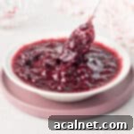 White bowl filled with berry compote on top of a pink plate.