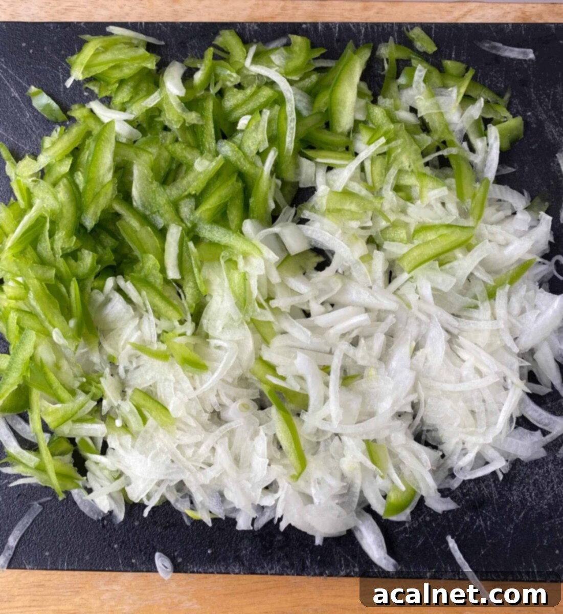 Philly Cheesesteak Poppers 7 Sliced green pepper and onion on a cutting board.