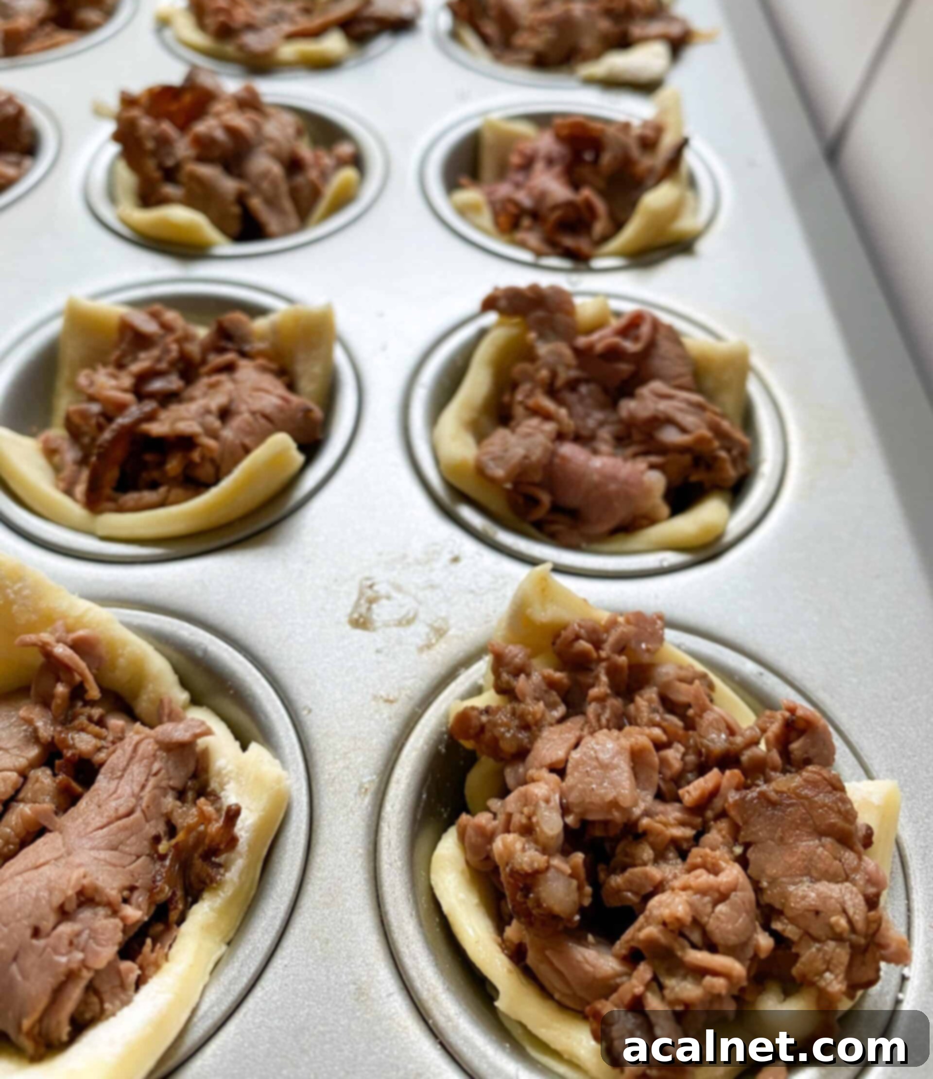Philly Cheesesteak Poppers 10 Mini muffin cups with cooked roast beef and puffed pastry in each one.