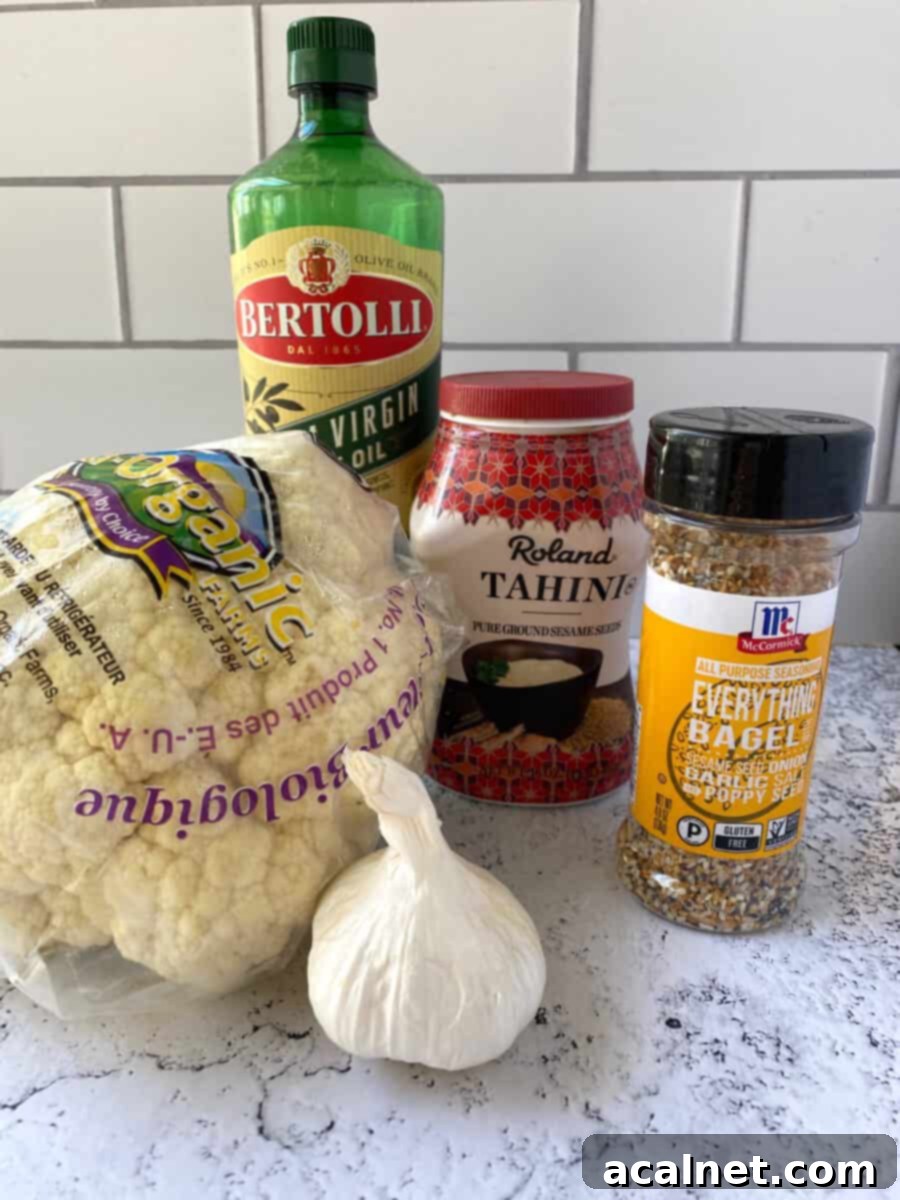 Everything-Spiced Cauliflower Hummus 3 Cauliflower hummus ingredients on a counter, including cauliflower florets, tahini, olive oil, garlic, and Everything Bagel Seasoning.