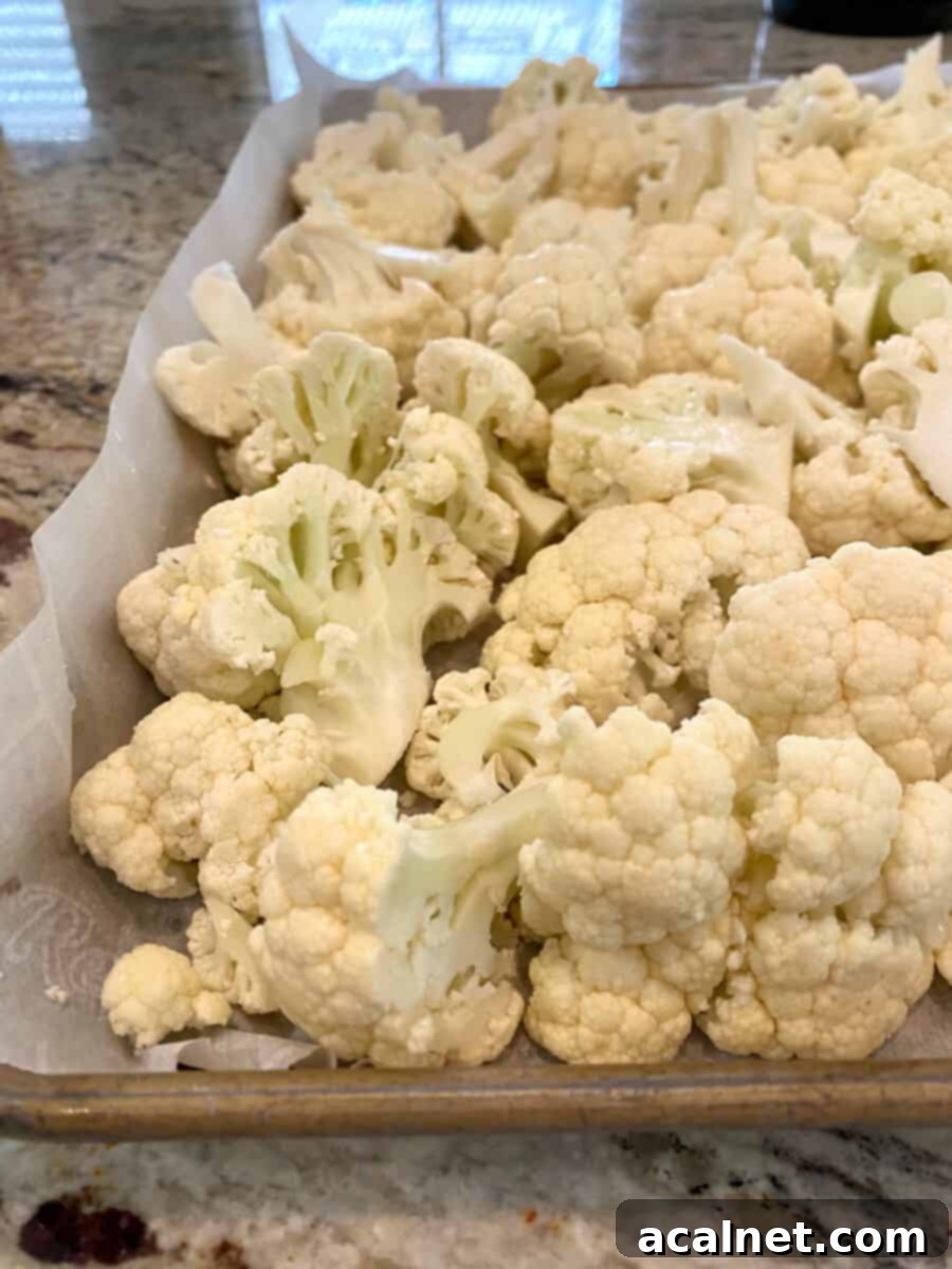 Everything-Spiced Cauliflower Hummus 4 Raw cauliflower florets arranged on a baking sheet lined with parchment paper, ready for roasting.