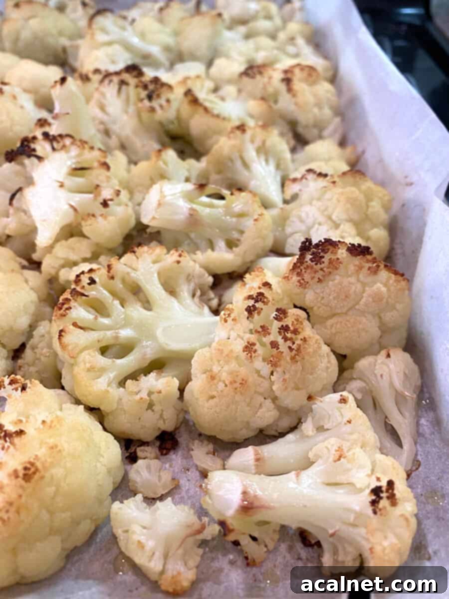 Everything-Spiced Cauliflower Hummus 6 Oven-roasted cauliflower florets with browned edges on a baking pan lined with parchment paper, showcasing perfect caramelization.