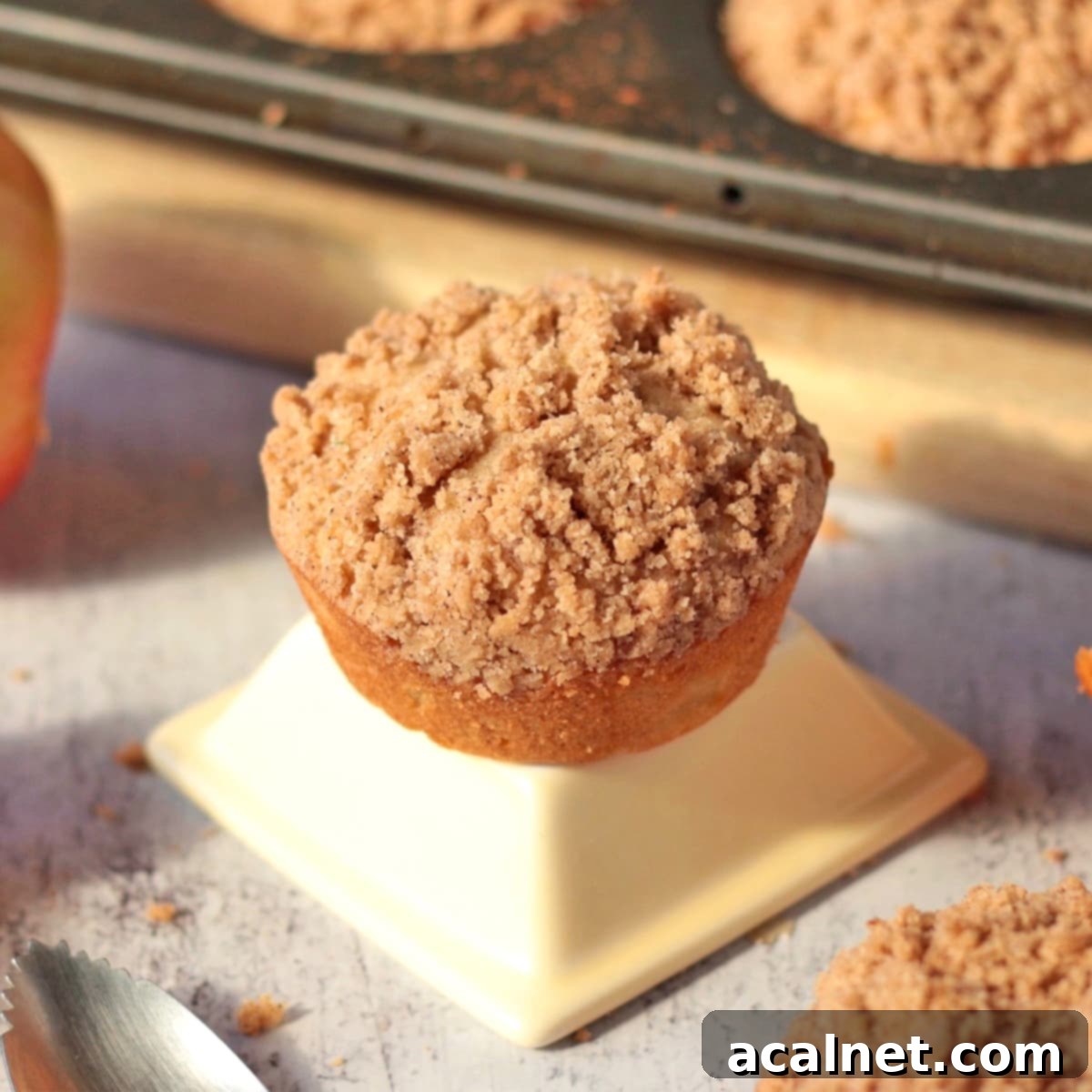 Heavenly Apple Cinnamon Streusel Muffins 2 One freshly baked apple cinnamon muffin with streusel topping on a white bowl, ready to be enjoyed.