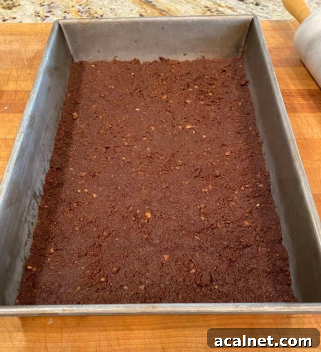 Spiced Pumpkin Swirl Cheesecake Bars 5 A thin, even layer of chocolate vanilla wafer crust pressed into the bottom of a 13x9 inch baking pan, ready for the filling.