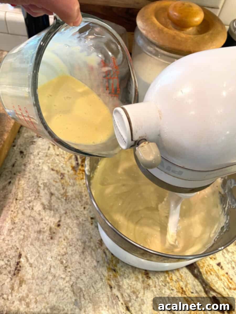 Spiced Pumpkin Swirl Cheesecake Bars 8 A mixing bowl showing eggs and vanilla extract being combined with sweetened condensed milk, next to a larger bowl with cream cheese mixture, illustrating the filling preparation.