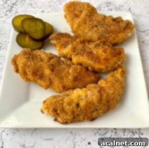 Golden Buttermilk Chicken Tenders 15 Chicken strips on a serving plate with pickles on the side