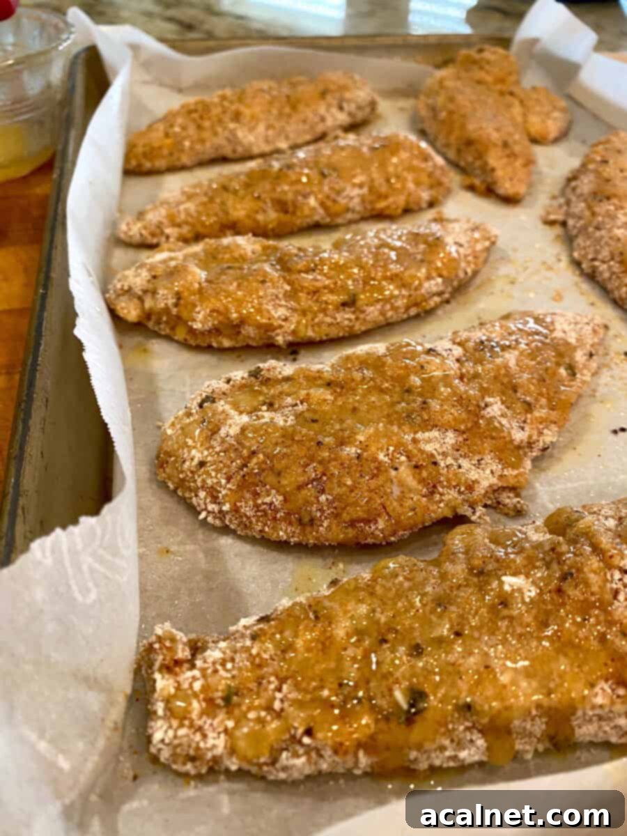 Golden Buttermilk Chicken Tenders 9 Chicken on parchment paper with a coating on melted butter covering the breaded strips
