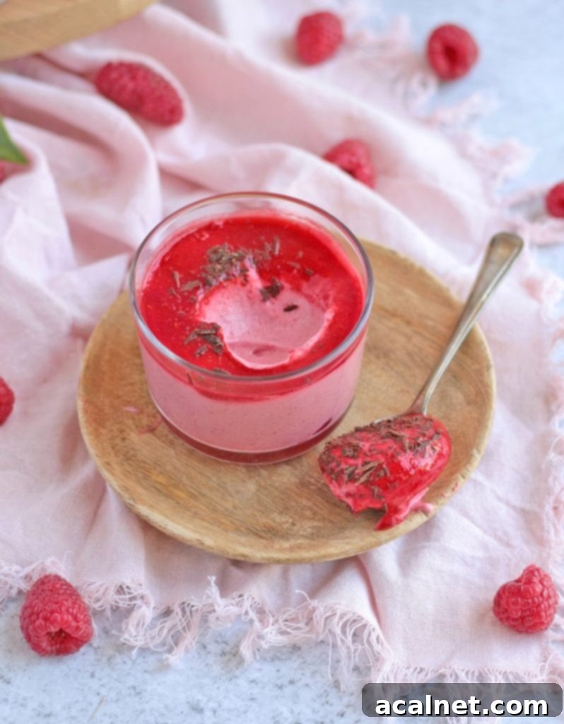 Luscious Raspberry Mousse 5 A spoon of raspberry mousse taken off the cup and dripping over the plate, showing its light texture.