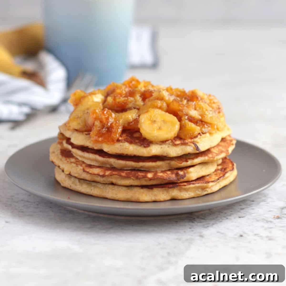 Banana Pancakes stacked on a grey plate and topped with honey caramelised bananas.